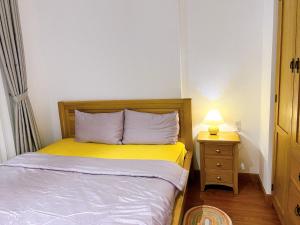 a small bedroom with a bed and a lamp on a night stand at Lá Homestay Apartment in Long Xuyên