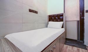 a small bedroom with a white bed with a wooden headboard at ZEST STAYS - MEADOW INN 1058 in Mumbai