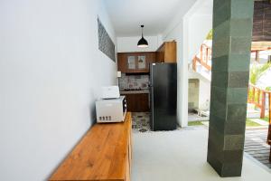 cocina con nevera negra y suelo de madera en Karang Island Villa, en Nusa Lembongan