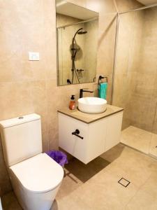 a bathroom with a toilet and a sink and a shower at Comfort Two bedroom Apartment In Lyneham in Canberra