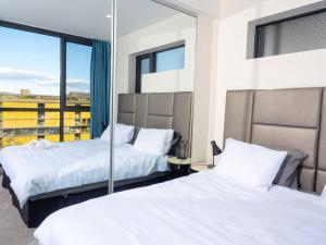 a bedroom with two beds and a large window at Comfort Two bedroom Apartment In Lyneham in Canberra