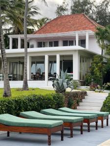 a house with green benches in front of it at BEACH FRONT VILLA in Malindi