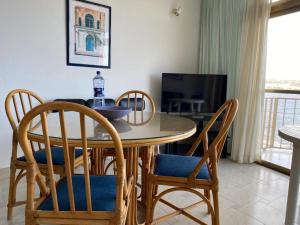 einen Esstisch mit Stühlen und einen TV in der Unterkunft Sea front apartment at Mellieha Bay, Malta! in Mellieħa