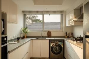 a kitchen with a washing machine in a sink at El Reino Elegant 2&3BHK Apartments 10 Minutes to Candolim with Pool & Kitchen, Wifi, Security in Verem +104 photos
