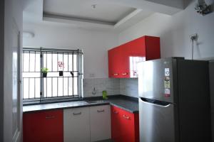 La cuisine est équipée de placards rouges et blancs et d'un réfrigérateur. dans l'établissement Aquavista lake view apartment, à Trivandrum