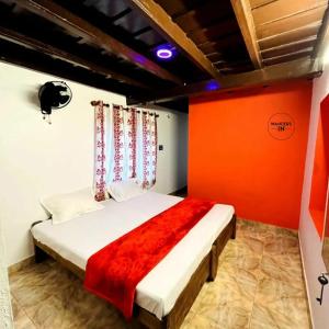 a bedroom with a bed with an orange wall at Wanders In Coffee Stays in Madikeri