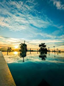 una piscina de agua con árboles y la puesta de sol en The Aurelia, en Gampola