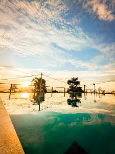 a pool of water with trees and the sky at The Aurelia in Gampola