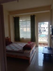 a bedroom with a bed and a large window at DAMEKI GUEST HOUSE , Shillong in Shillong