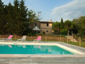a swimming pool with two chairs and a house at Agriturismo Ai Prati in Perugia