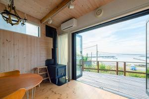 葉山町にある南葉山 - Seaside Cabin in Minami-hayamaのテーブルと大きなスライド式ガラスドアが備わる客室です。
