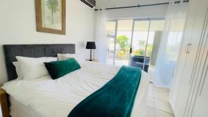 a bedroom with a large white bed with green pillows at Casablanca Guest House in Durban