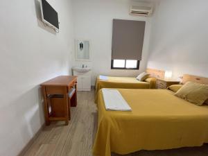 Habitación pequeña con 2 camas y lavamanos en Pensión Galicia en Badajoz
