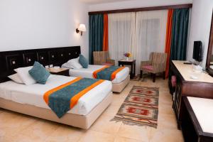 Habitación de hotel con 2 camas y escritorio en Turquoise Beach Hotel en Sharm El Sheikh
