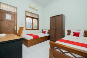a room with two beds and a counter in it at RedDoorz Syariah at Jalan Sunan Giri Tuban in Tuban