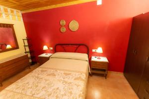 ein Schlafzimmer mit einer roten Wand mit einem Bett und zwei Tischen in der Unterkunft Vivienda Puente de Tramaya in Cazorla