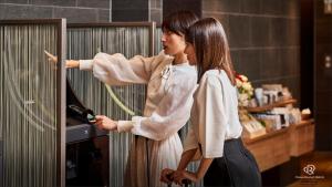 twee vrouwen die in een winkel staan te kijken naar een fles wijn bij Daiwa Roynet Hotel Shimbashi in Tokyo