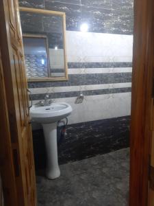 y baño con lavabo blanco y espejo. en Sita Chalet Manali en Manāli