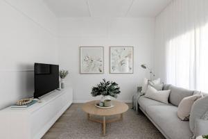 a white living room with a couch and a tv at Casa Wilde in the Hunter in Cessnock
