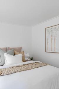 1 cama blanca con almohadas y una foto en la pared en Casa Wilde in the Hunter en Cessnock