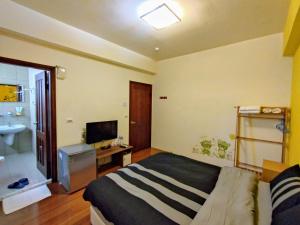 a bedroom with a bed and a television and a sink at 1986 Travel Hall in Tainan