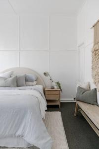 Dormitorio blanco con cama y banco en Casa Wilde in the Hunter en Cessnock