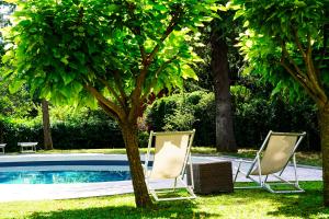 duas cadeiras e uma árvore ao lado de uma piscina em Villa Bottacin em Trieste