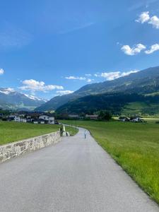 a person walking down a road with mountains in the background at Gasthof Neumeister in Stumm
