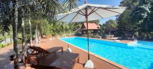 a swimming pool with chairs and an umbrella next to it at Pasak River House Home stay 