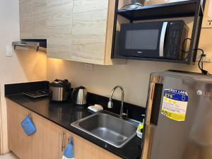 eine kleine Küche mit einer Spüle und einer Mikrowelle in der Unterkunft Elane's Staycation -Mezza 2 1 br in Manila