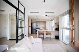 een woonkamer met een witte bank en een keuken bij Coziest 2 Bedroom In Collective, Dubai Hills by 2ndhome in Dubai