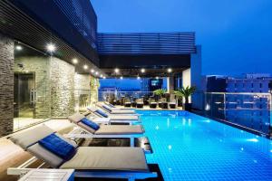 a swimming pool with chaise lounge chairs on a building at MarQ Luxury Apartment by NEST Group in Ho Chi Minh City