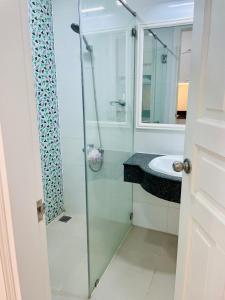 uma casa de banho com uma cabina de duche em vidro e um lavatório. em Căn hộ Ocean Vista 1br Garden View - SeaHome em Phan Thiet