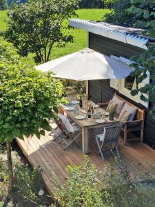 Una terraza de madera con una mesa y una sombrilla. en Countryhouse Lake Attersee - Traumhaft schöne Lage - Bezauberndes Hideaway, en Unterach am Attersee 202 fotos más