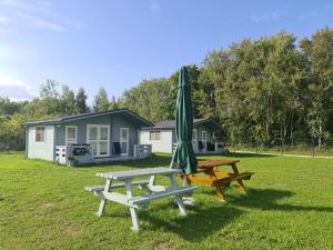 a picnic table with a green umbrella and a picnic bench at Domki Przy Marinie Wapnica 6 km od Międzyzdrojów in Wapnica