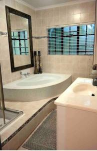 La salle de bains est pourvue d'une baignoire, d'un lavabo et d'un miroir. dans l'établissement Stadigies Self-Catering Accommodation, à Marloth Park