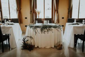 uma mesa numa sala com mesas brancas e flores em Casa Maria Magdalena em Lipova