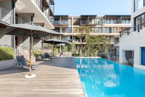 a swimming pool with an umbrella next to a building at Drieks' Place in Cape Town