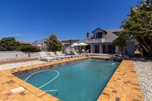 a swimming pool with chairs and a house at 38 on Westcliff in Hermanus