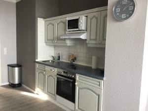 a kitchen with white cabinets and a microwave at Hafenwohnung in Borgwedel