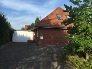 ein rotes Backsteinhaus mit einer weißen Garage in der Unterkunft Fewo Zur Ilmenau in Melbeck