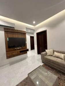 a living room with a couch and a flat screen tv at شقق سحاب الفندقية in Qal'at Bishah