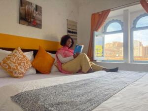 a woman sitting on a bed reading a book at Jaisalmer Hostel Crowd in Jaisalmer