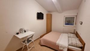 een kleine slaapkamer met een bed en een bureau bij Apartments and rooms Niki 2 in Kaštela