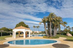 a swimming pool with a gazebo and palm trees at Almela's in Santa Pola