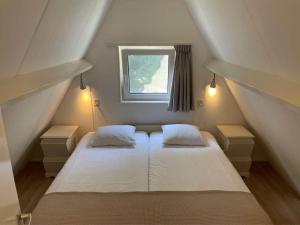 a attic bedroom with two beds and a window at Holiday home Landgoed Eysinga State 4 in Sint Nicolaasga