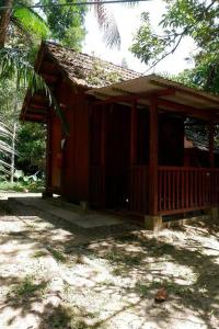 a small wooden cabin with a porch in the woods at Jungle Zen Janda Baik Campsite in Kampung Janda Baik