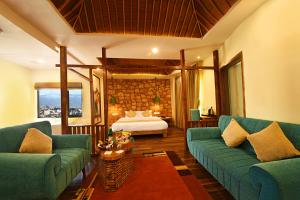 a living room with two green couches and a bed at Woodapple Hotel and Spa in Kathmandu