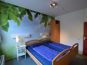 a bedroom with a blue bed with a tree painted on the wall at Welcoming Mansion near Forest in Bergeijk in Bergeijk