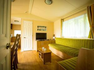 uma sala de estar com um sofá verde e uma televisão em Recreatiepark Duinhoeve 4 em Udenhout
